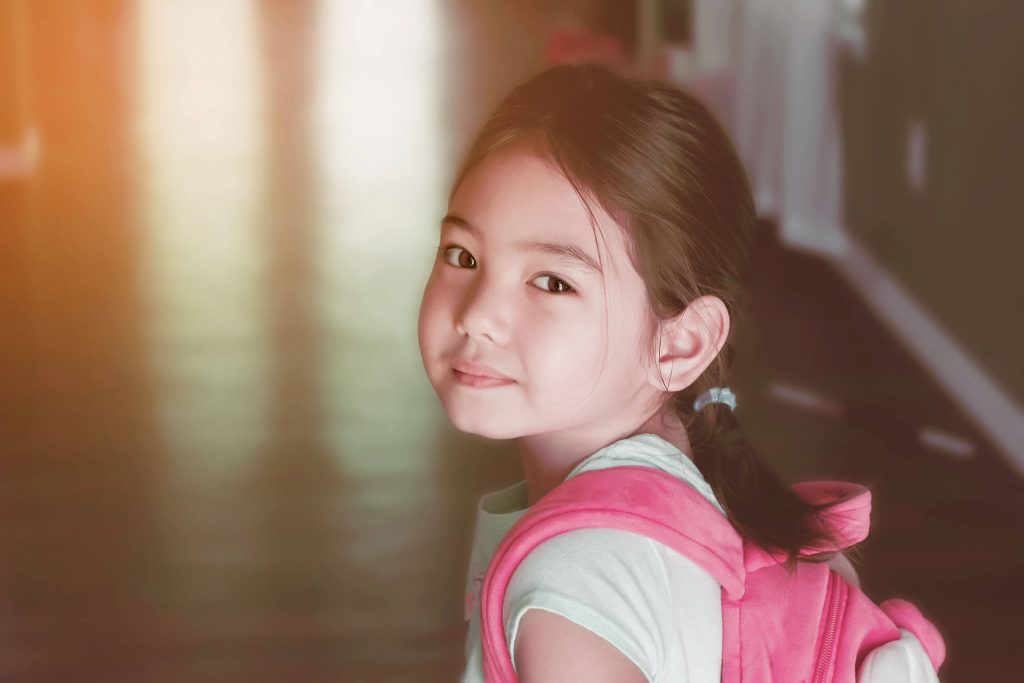 Closeup of young girl smiling and wearing a pink backpack