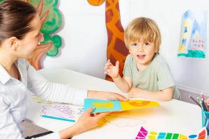 child looks at educational items with therapist
