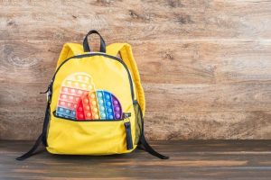 A yellow sensory backpack with fidget toys sticking out
