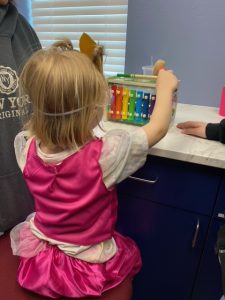 Toddler girl in a pink dress playing with a toy